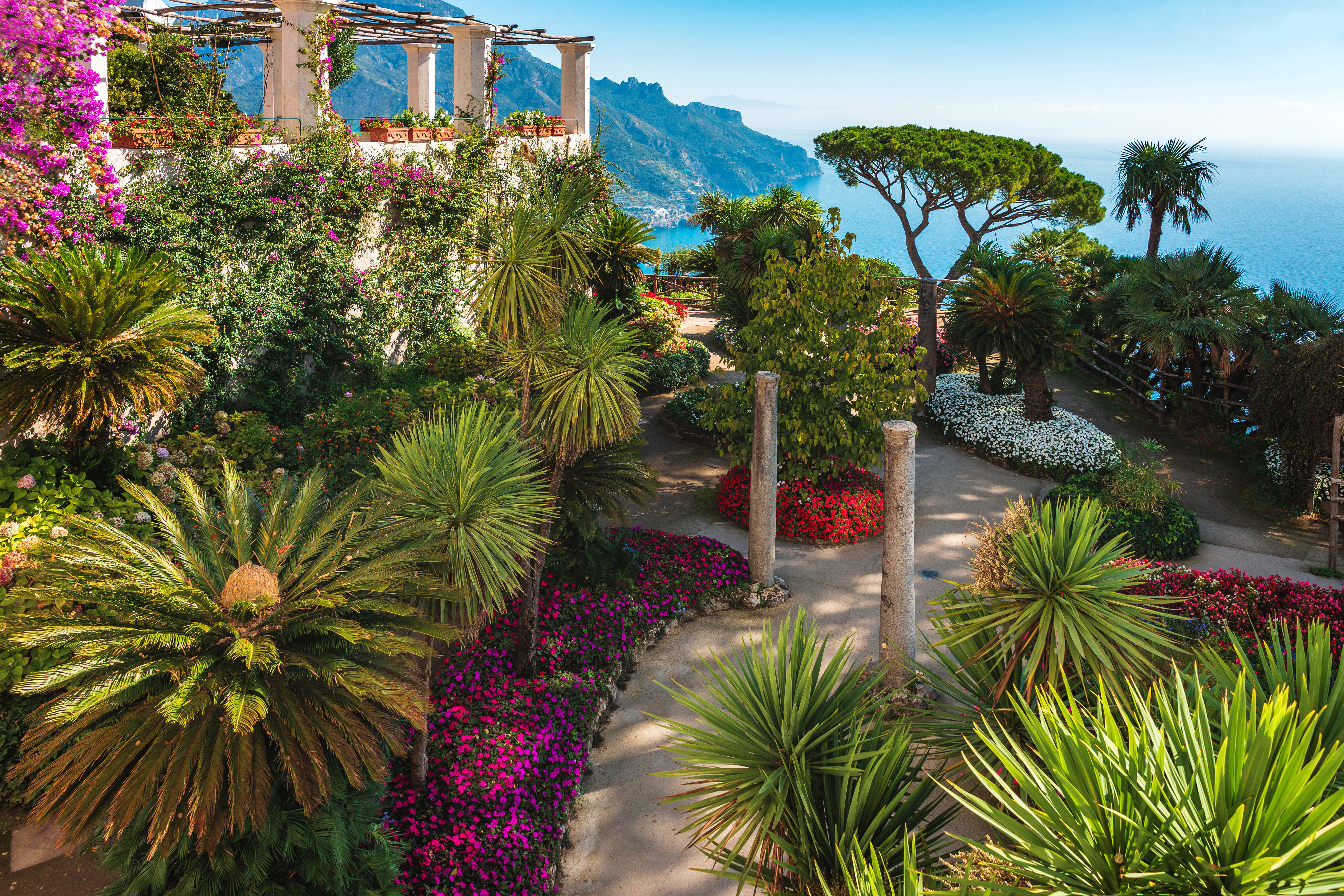 De smukke terrассеhaver ved Villa Rufolo i Ravello på Amalfikysten med farverige blomster, palmer og udsigt over Middelhavet