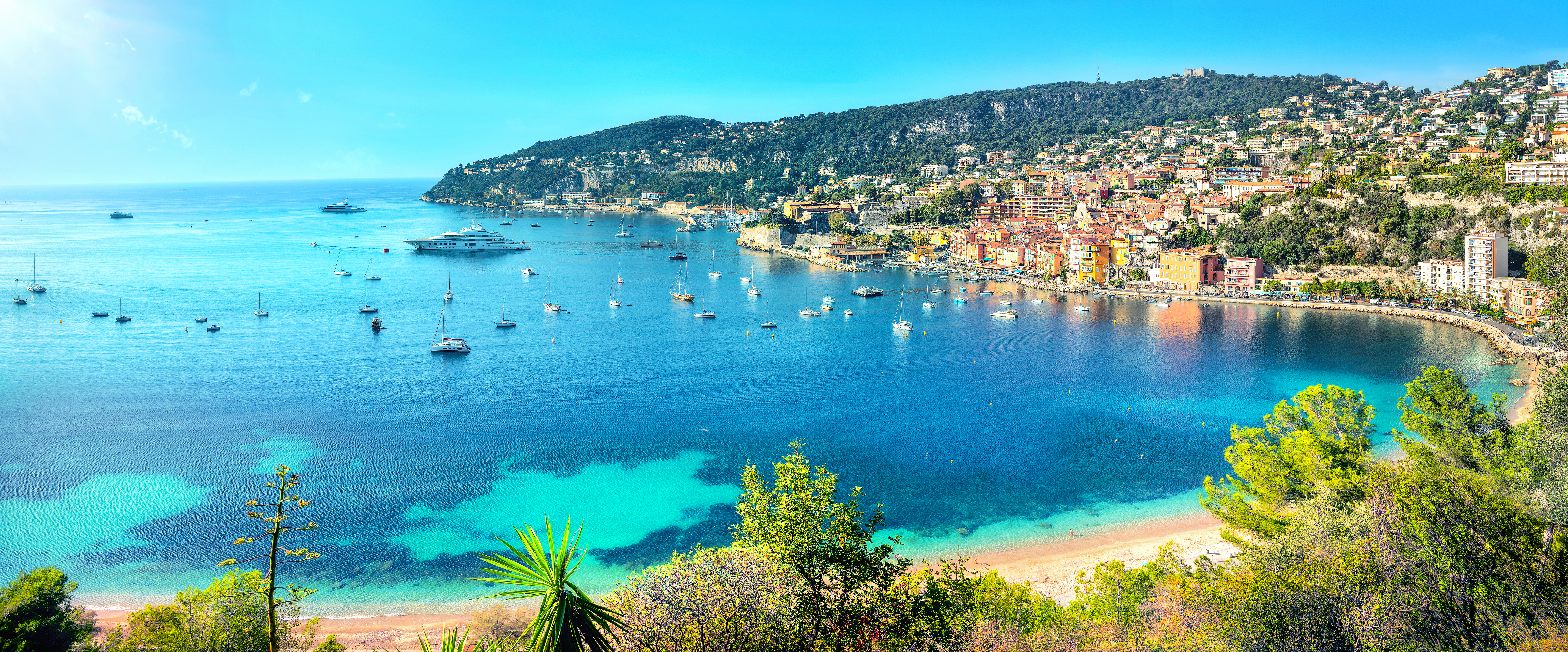Panoramisk udsigt over den azurblå bugt og feriebyen Villefranche sur Mer på den franske riviera med farverige huse og både i marinaen