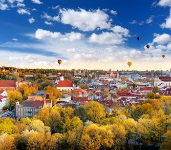 Betagende efterårsudsigt over Vilnius' gamle bydel med farverige varmluftsballoner svævende over de historiske bygninger, set fra Gediminas-tårnet