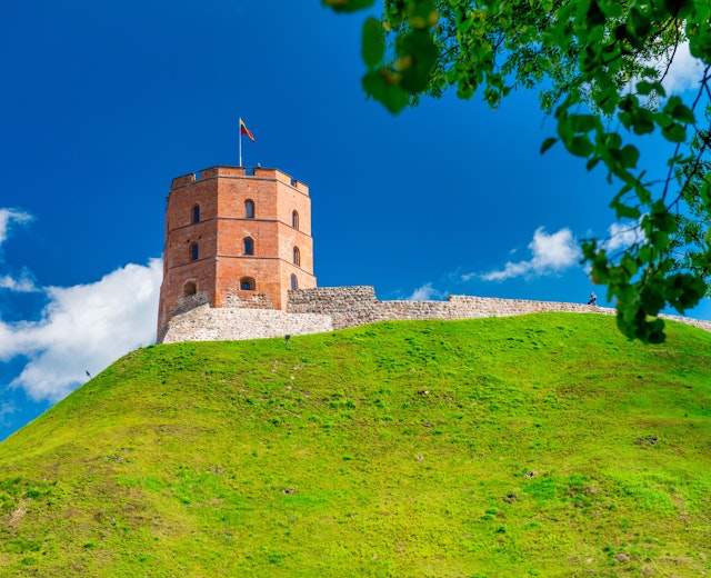 Historisk Vilnius slot med grønne bakker under blå himmel i Litauen