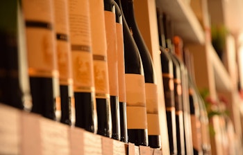 Vinflasker arrangeret på træhylder i en hyggelig vinbutik med et udvalg af champagne og mousserende vine