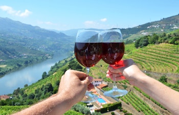 To vinglas holdes op mod de smukke terrasserede vinmarker i Douro-dalen, Portugal - et berømt vinområde kendt for portvin