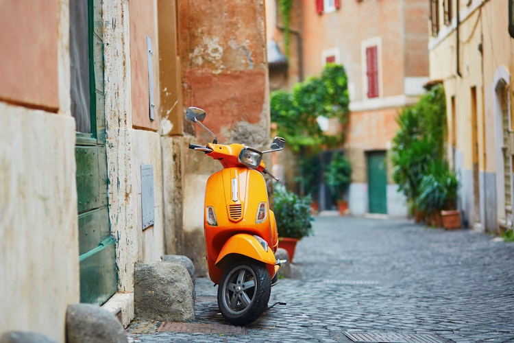 Klassisk orange scooter parkeret på en charmerende gade i Trastevere-kvarteret i Rom, Italien