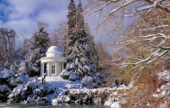 Historisk tempel i sneklædt vinterlandskab i Bergpark Wilhelmshöhe i Kassel, Tyskland med frosset vandhul og snedækkede træer