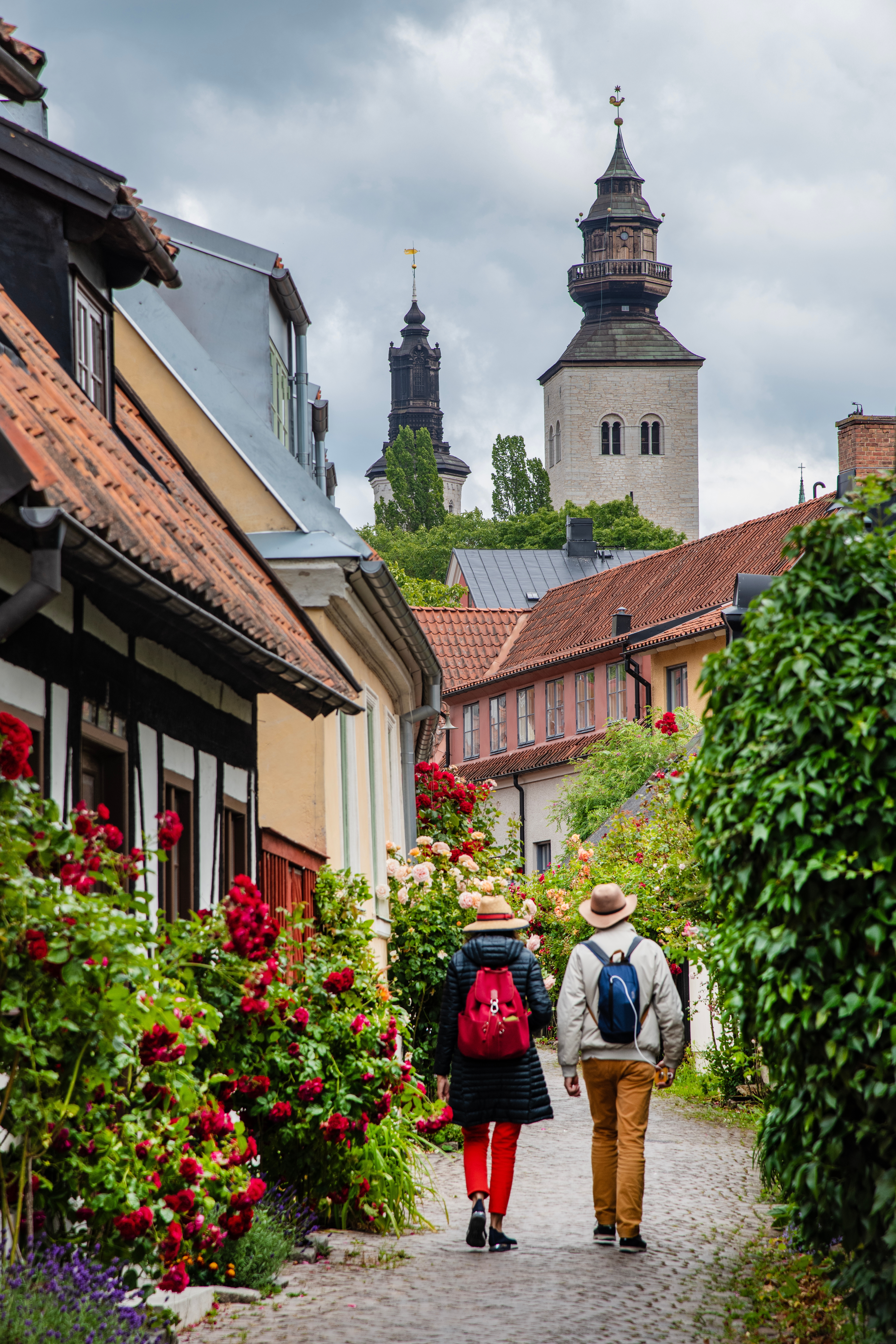 Par der vandrer gennem historisk brolagt gade i Visby på Gotland med middelalderlige kirketårne