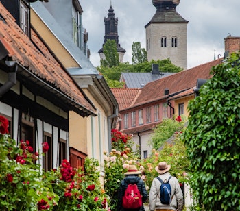 Par der vandrer gennem historisk brolagt gade i Visby på Gotland med middelalderlige kirketårne