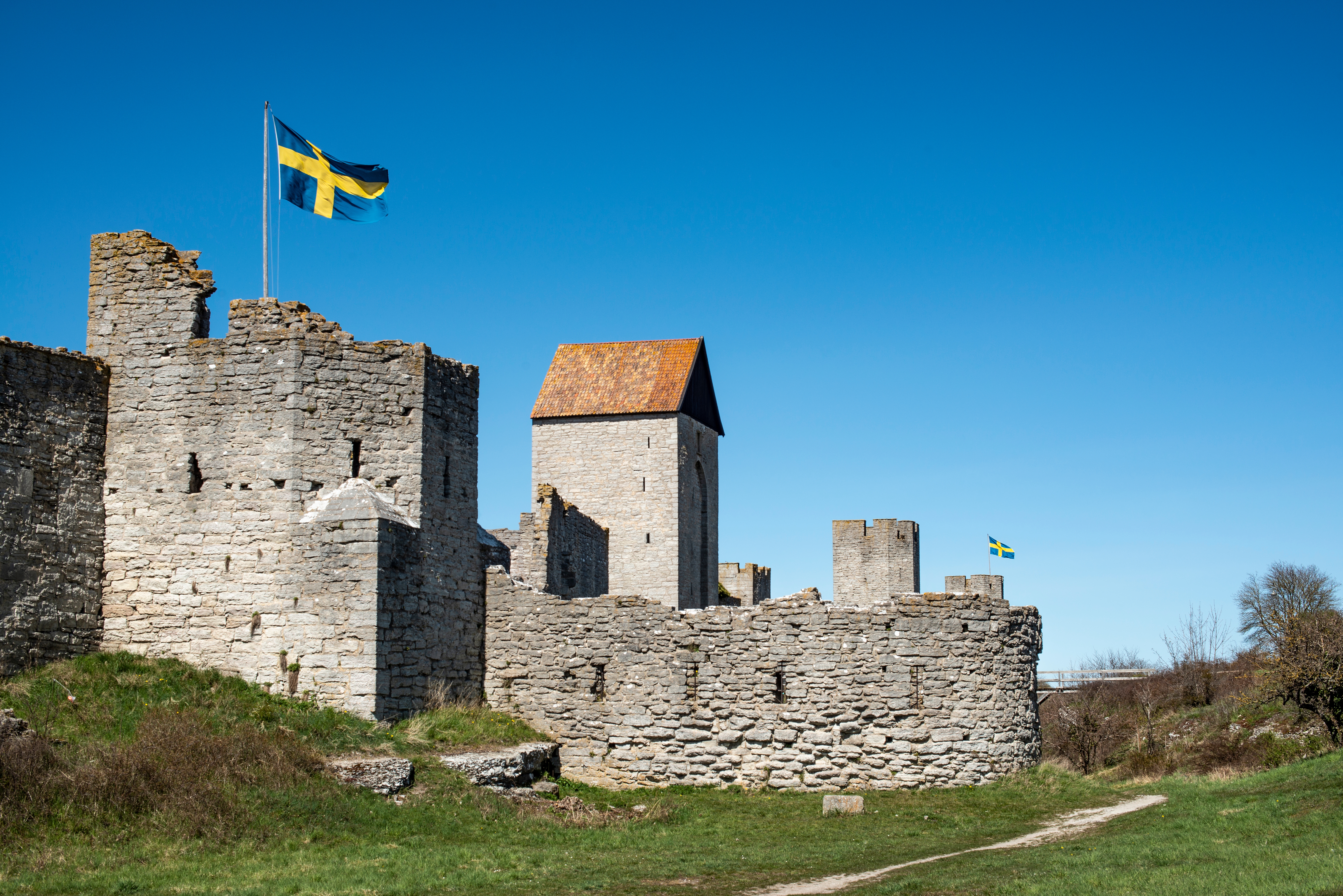 Middelalderlige borgruiner med svensk flag på Gotland, historisk fæstning med stenmure og tårne