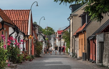 Idyllisk middelalderlig gade i Visby på Gotland med farverige huse, brostensbelægning og blomstrende stokroser på en solrig sommerdag