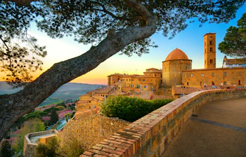 Panoramaudsigt over den middelalderlige bjergby Volterra ved solnedgang med kuppelkirke og tårn i Toscana, Italien