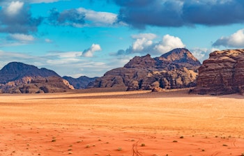 Majestætisk ørkenlandskab i Wadi Rum, Jordan med imponerende sandstensklipper, beduintelte og dramatisk himmel