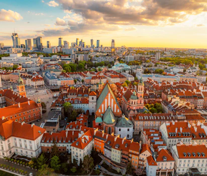 Luftfoto af Warszawas gamle bydel ved solnedgang med røde tage og moderne skyline i baggrunden, Polen