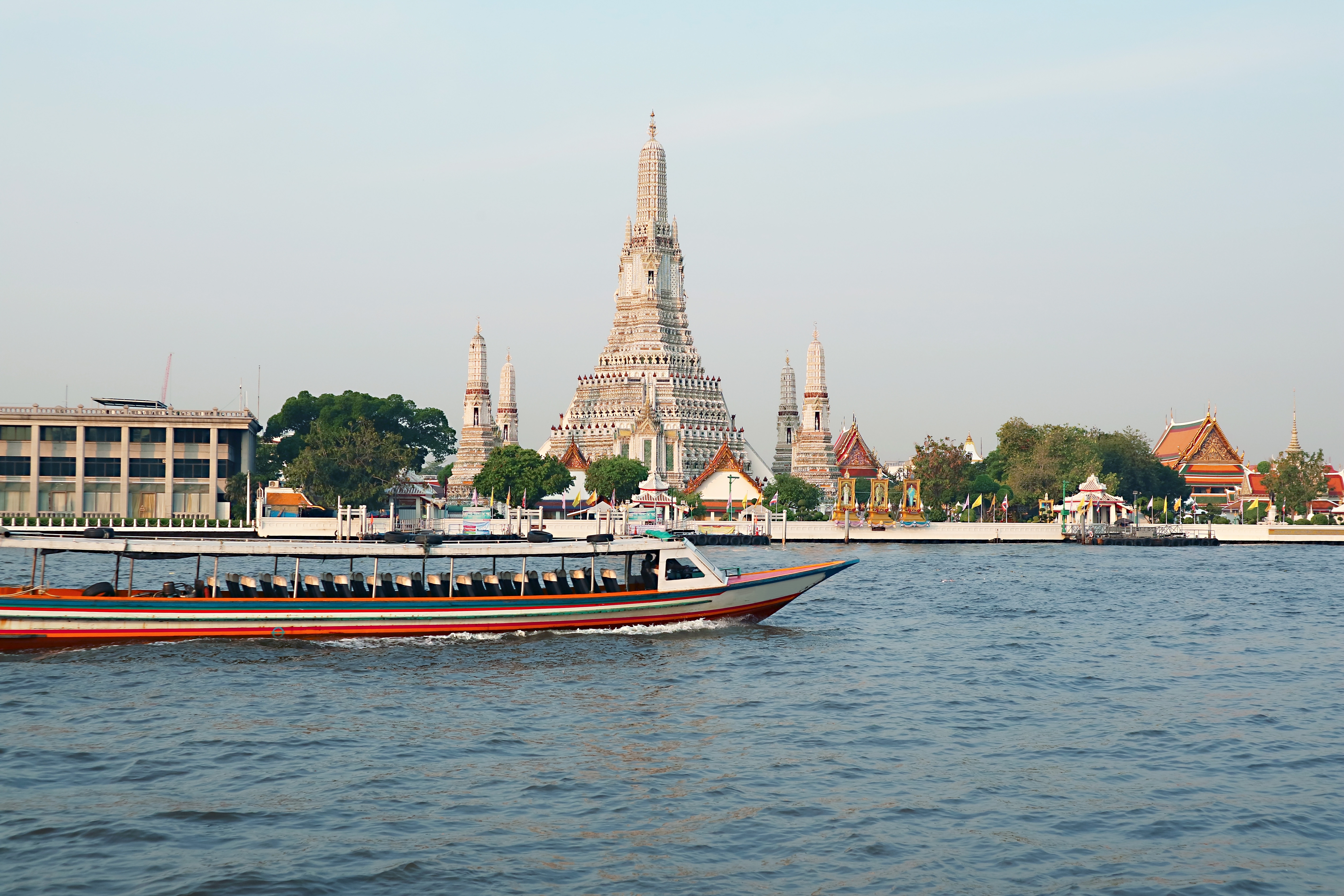 Traditionel thailandsk baad paa Chao Phraya floden med Wat Arun tempel i Bangkok