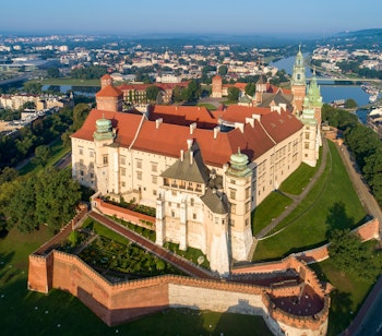 Luftfoto af det historiske Wawel-slot og katedralen i Krakow ved solopgang med Vistula-floden i baggrunden