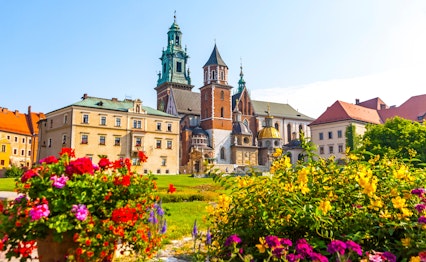 Wawel Kongeslot i Krakow med farverige sommerblomster i forgrunden og blå himmel