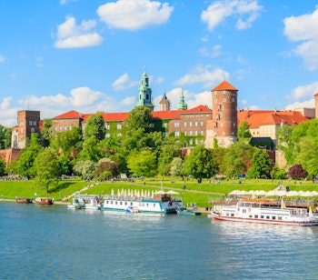 Majestætisk udsigt over det historiske Wawel-slot og katedralkompleks beliggende på bredden af Vistula-floden i Krakow, Polen, omgivet af frodige grønne områder