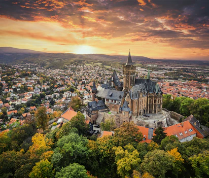 Luftfoto af det historiske Wernigerode Slot med udsigt over den maleriske by i Harzen, Tyskland ved solnedgang