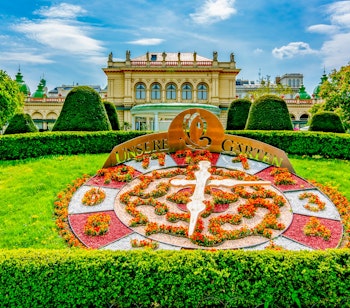 Det berømte blomsterur i Stadtpark i Wien med farvestrålende blomster arrangeret i et cirkulært mønster omgivet af velplejet grøn græsplæne, en populær seværdighed i Østrigs hovedstad