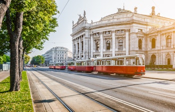 Det historiske Burgtheater og den røde sporvogn på Wiens berømte Ringstrasse ved solopgang i Østrig