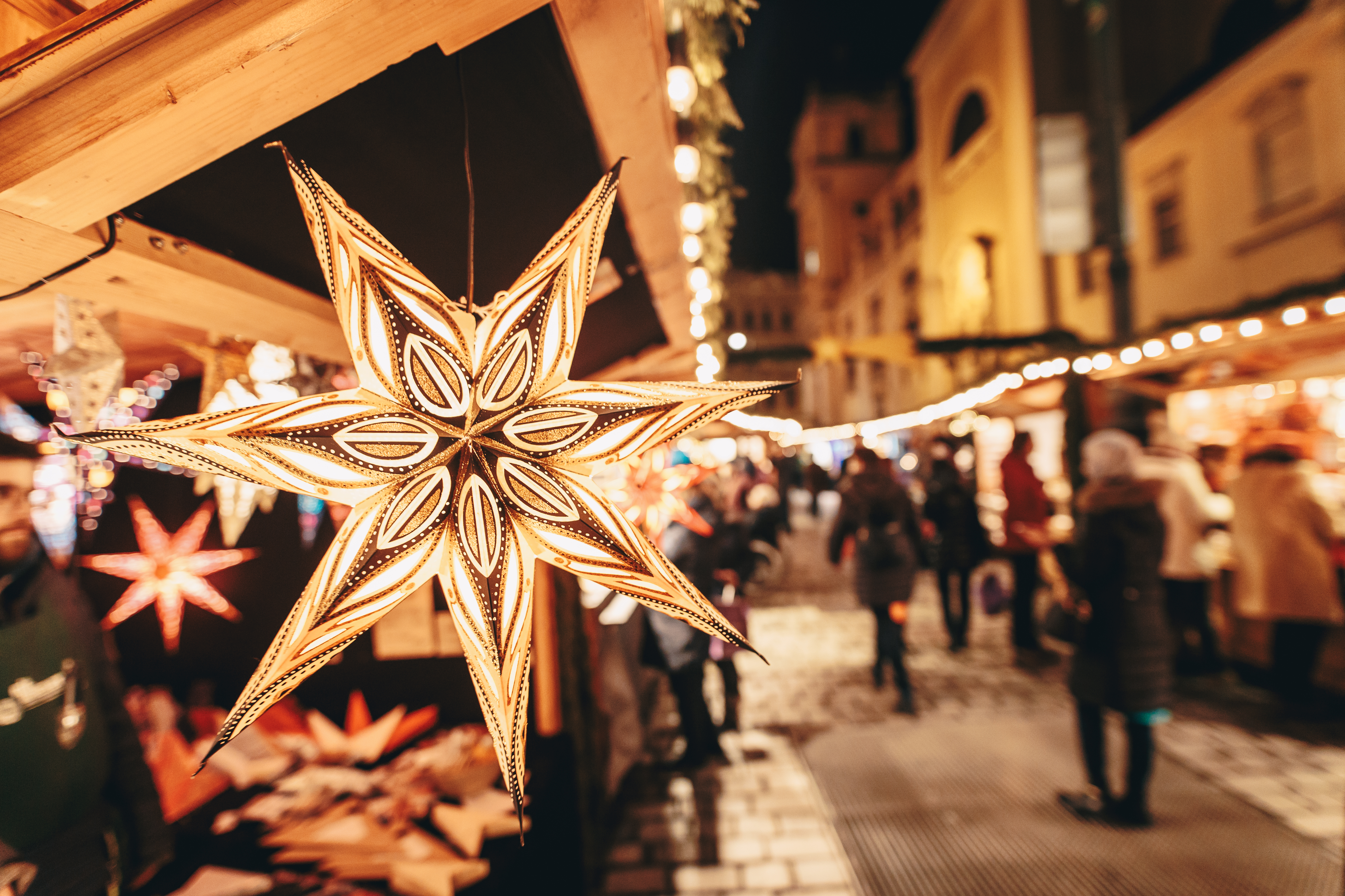 Stjerne-formet papirlanterne på julemarked i Wien om aftenen med traditionelle træboder