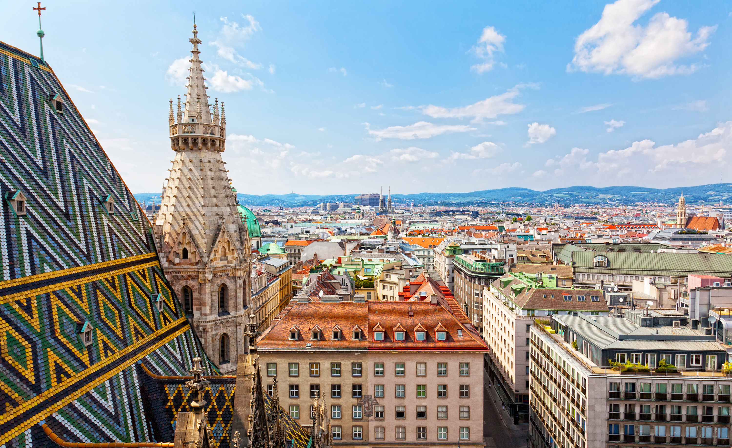 Betagende panoramaudsigt over Wiens historiske bycentrum med farverige tage og bygninger set fra Stephansdom-katedralens tårn på en solrig sommerdag