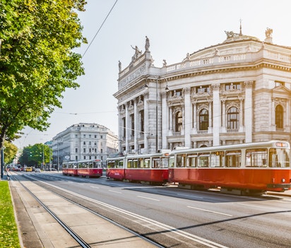 Det historiske Burgtheater og den ikoniske røde sporvogn på Wiens berømte Ringstrasse ved solopgang i Østrig