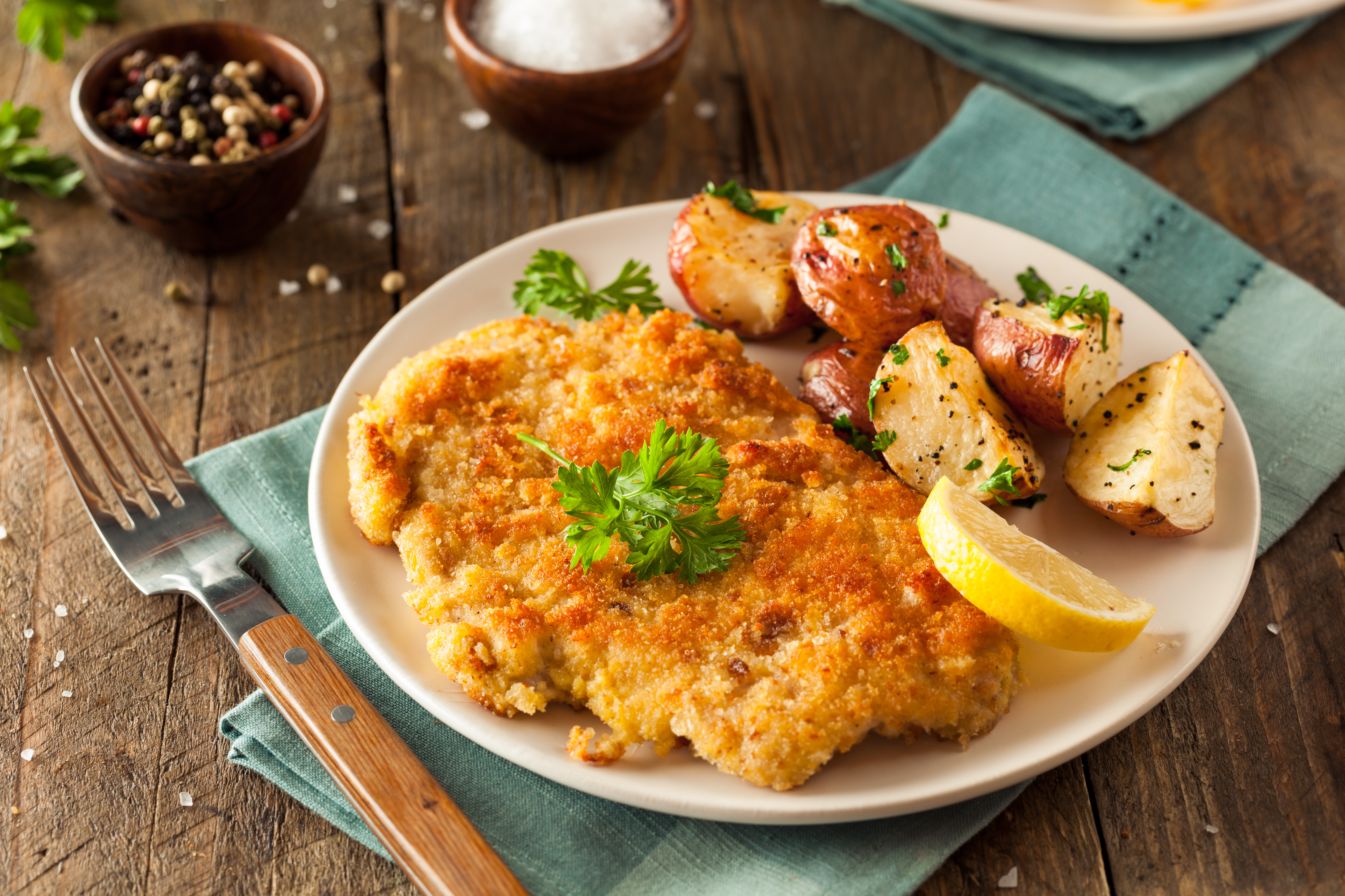 Klassisk wiener schnitzel med sprød panering serveret med stegte kartofler og citron, en ikonisk østrigsk specialitet der er et must at smage på rejsen til Wien