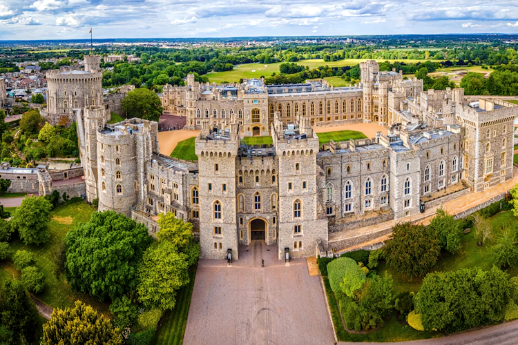 Luftfoto af Windsor Slot med middelalderlige taarne og groenne haver i England