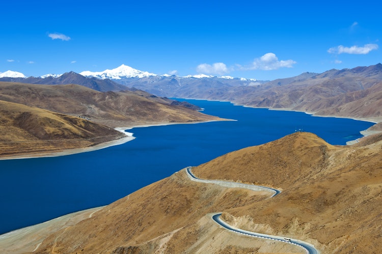 Fantastisk udsigt over turkisblå Yamdrok sø med snoet bjergvej gennem de tibetanske Himalayas