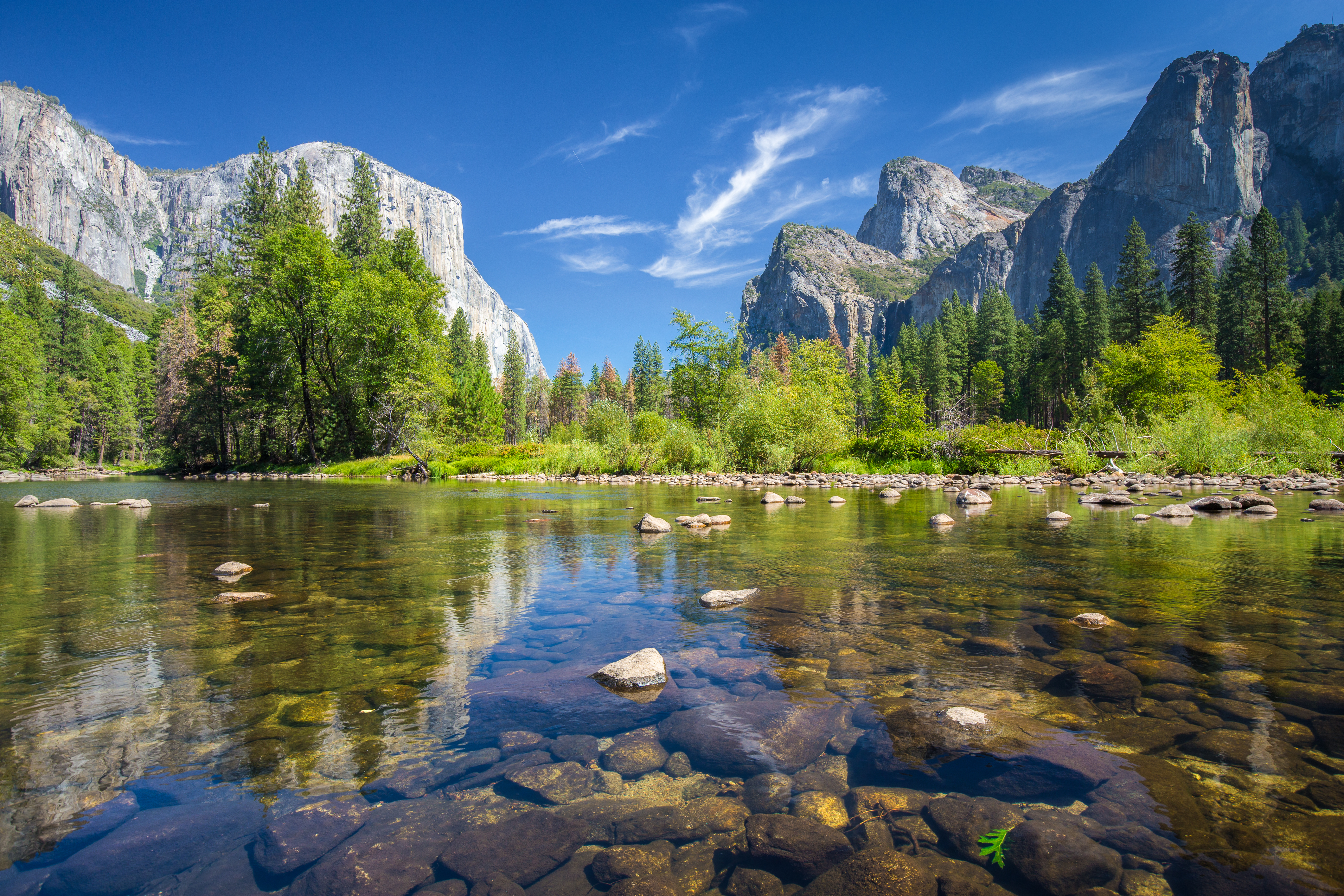Krystalklart bjergvand med refleksioner af imponerende granitfald og grøn skov i Yosemite nationalpark