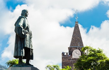 Statue af Joao Goncalves Zarco, Madeiras grundlægger, på Arriaga avenuen med Se katedralens ur i baggrunden, Funchal, Portugal