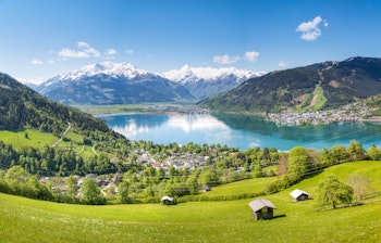 Betagende panoramaudsigt over den østrigske alpeby Zell am See med dens krystalklare bjergø omgivet af grønne bjerge og charmerende bygninger i Salzburg-regionen