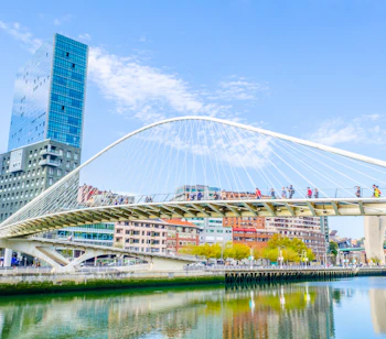 Den ikoniske hvide Zubizuri-bro i Bilbao, Spanien, designet af Calatrava, med mennesker der krydser over Nervion-floden